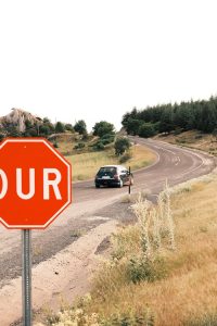 Car travels on a scenic rural road with a prominent stop sign.